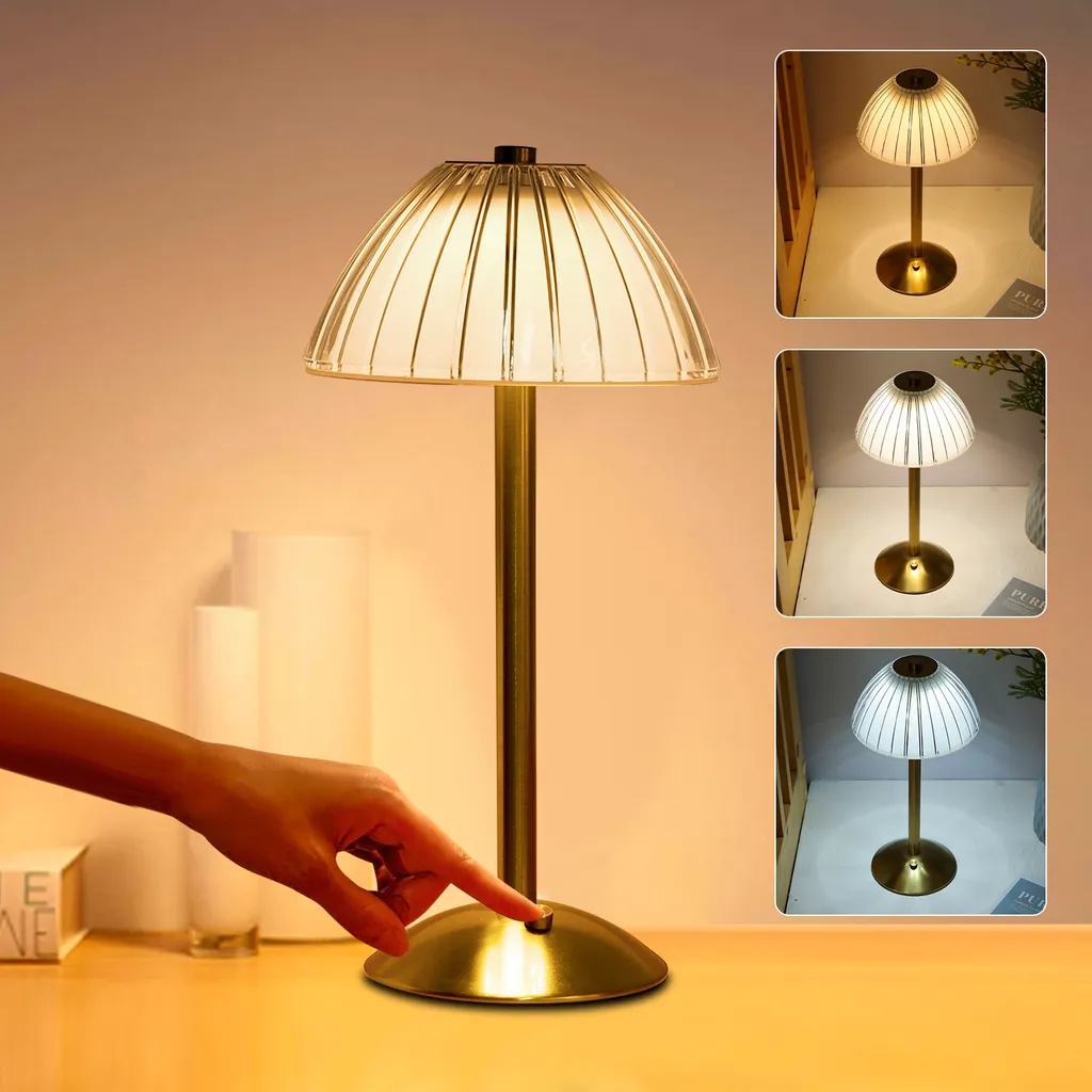 Eine Hand berührt den Schalter einer goldenen Tischlampe mit geripptem Schirm und drei Farbtönen rechts.
