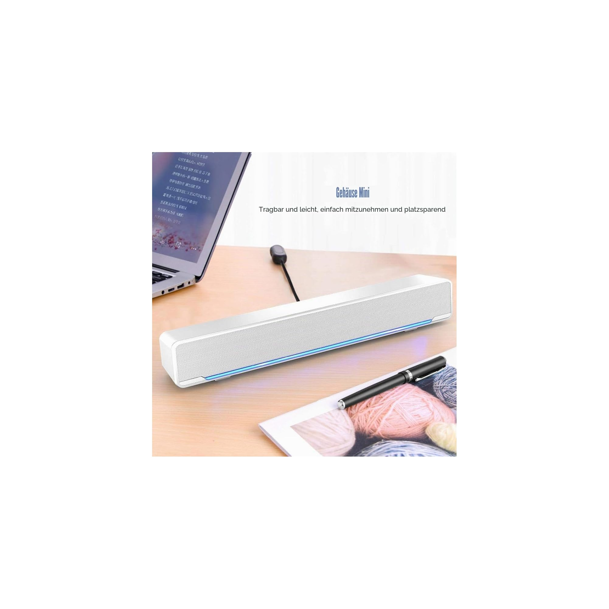 Eine weiße Mini-Soundbar und ein schwarzer Stift liegen auf einem Holztisch vor einem Laptop.