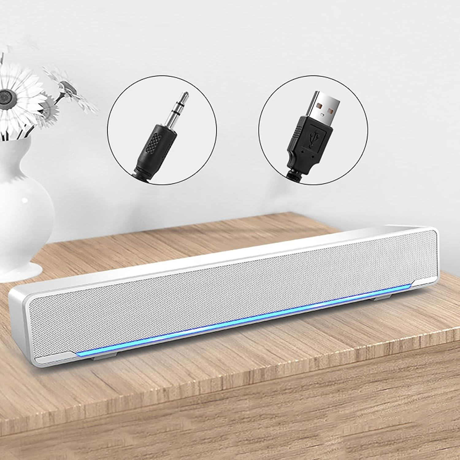 Eine weiße Soundbar mit blauer LED-Leiste steht auf einem Holzschreibtisch, mit eingekreisten Audio- und USB-Kabeln.