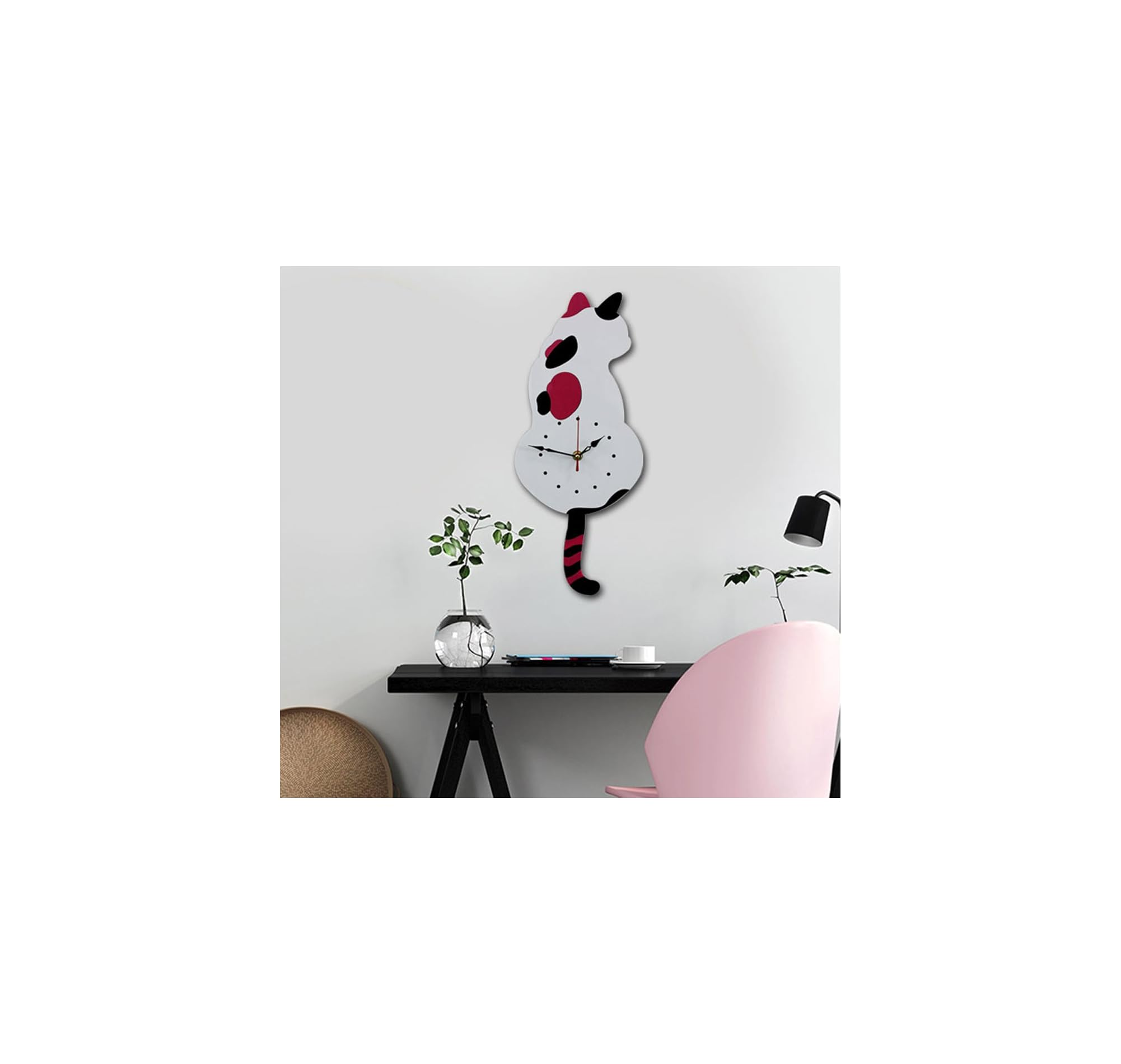 Eine weiße Wanduhr in Katzenform mit hängendem Schwanz hängt über einem schwarzen Tisch mit Pflanzen und einem rosa Stuhl.