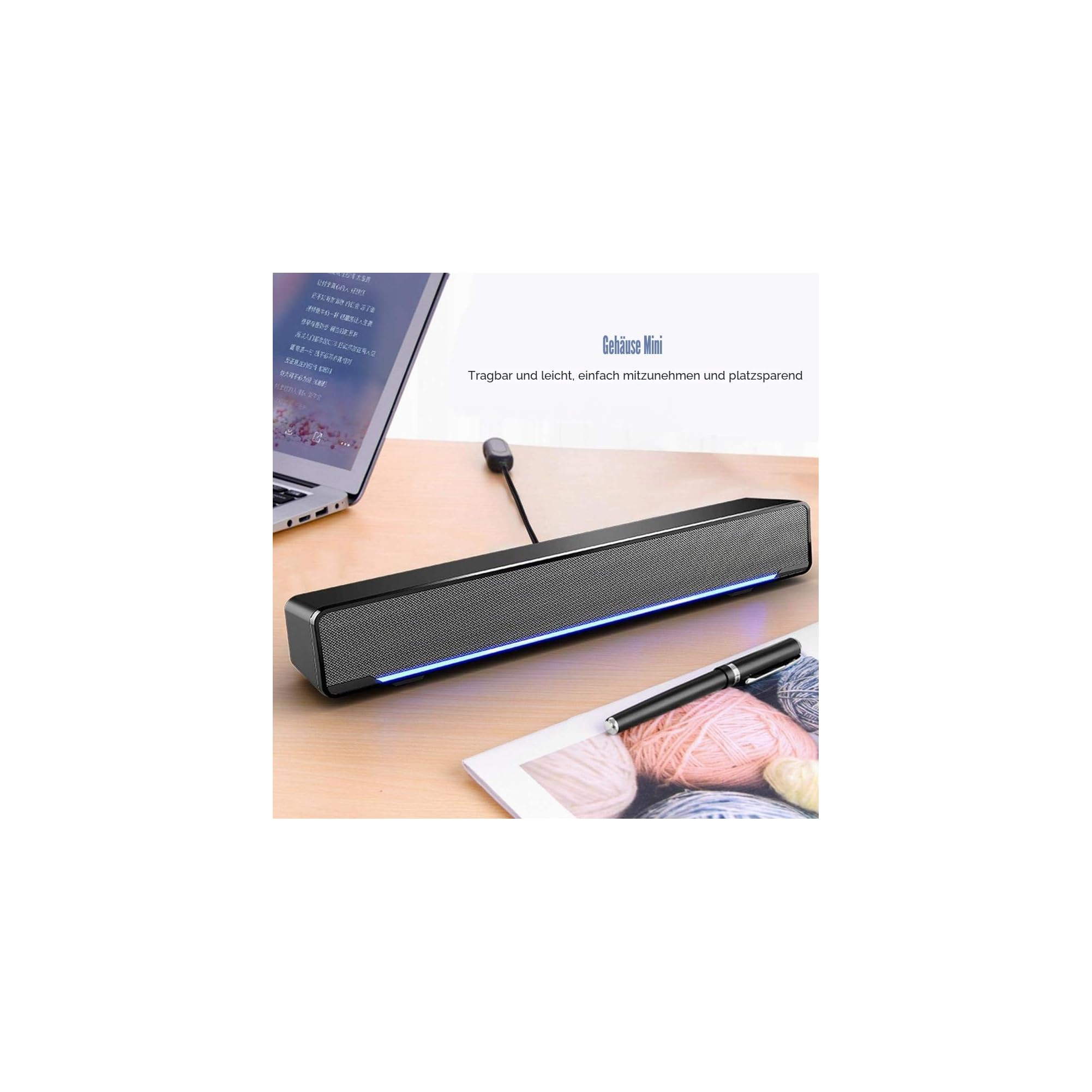 Eine lange schwarze Soundbar mit blauer Beleuchtung liegt auf einem Holztisch neben einem Laptop und einem Stift.