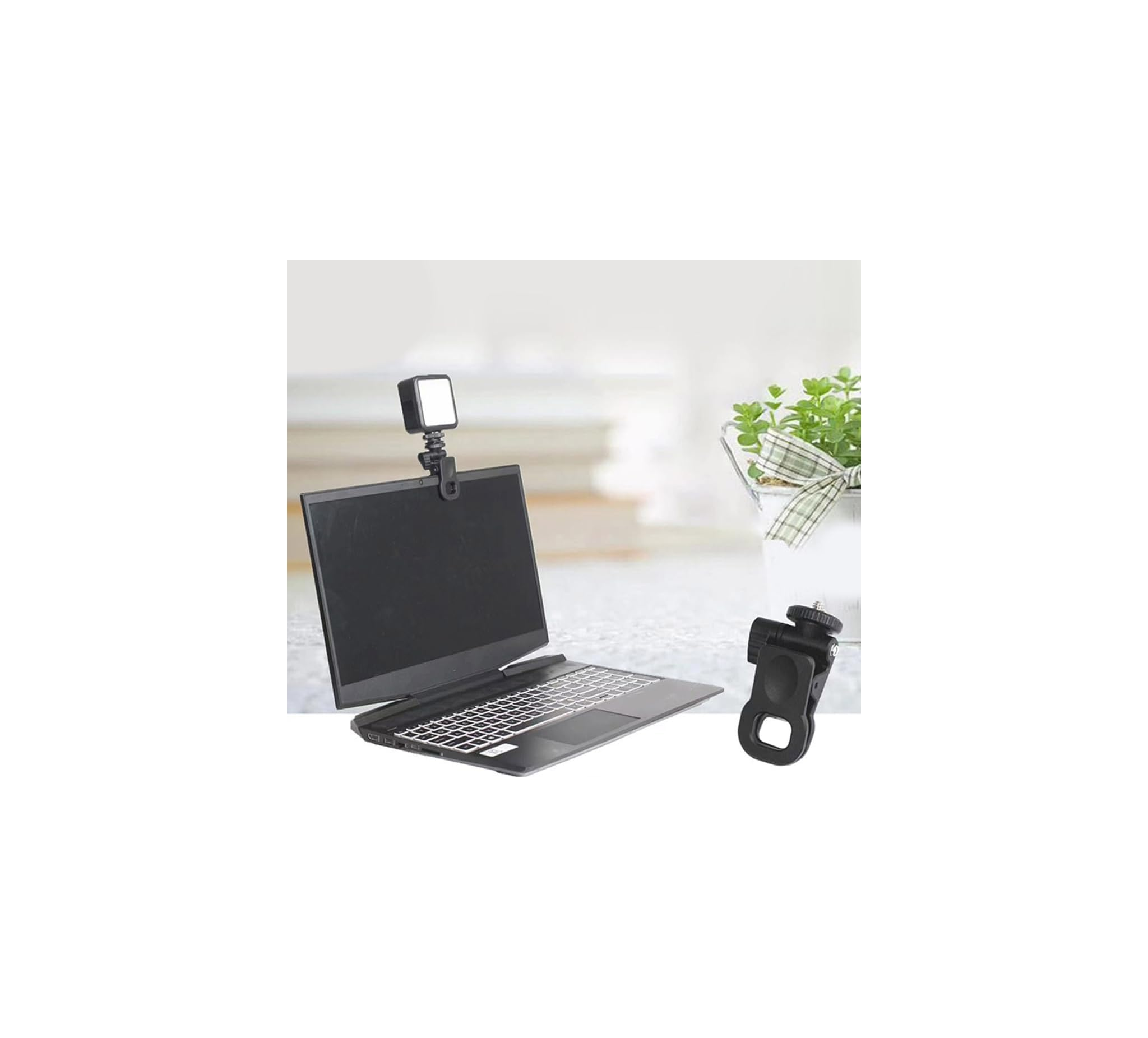Ein Laptop steht auf einem Tisch mit einer kleinen Leuchte am Bildschirm und einem schwarzen Klipp im Vordergrund.