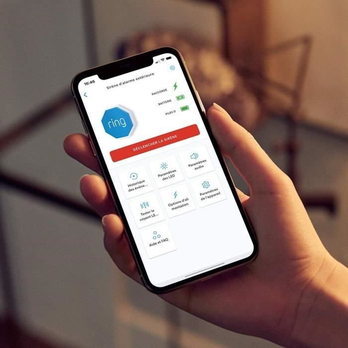 Una mano sostiene un teléfono inteligente que muestra la interfaz de la aplicación Ring con opciones.