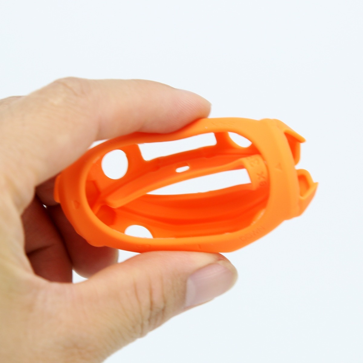 Eine Hand hält eine flexible, orangefarbene Schutzhülle aus Silikon vor weißem Hintergrund.