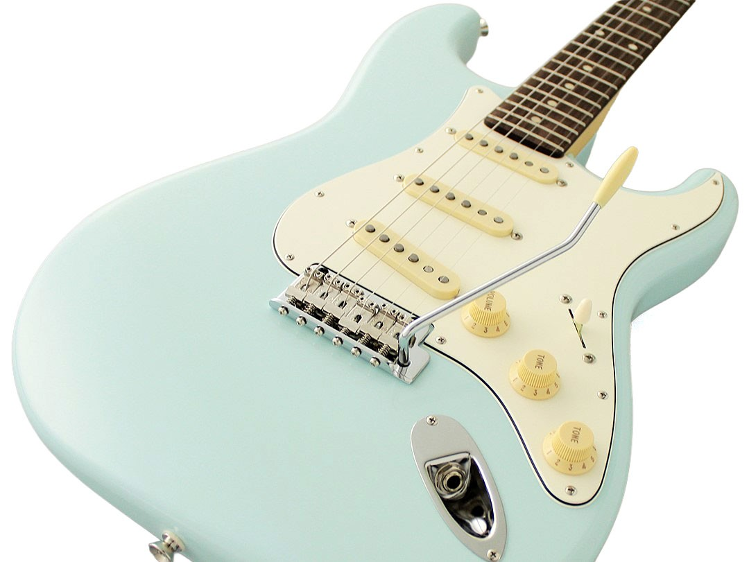 Beyaz arka planda beyaz korumalı, krom köprülü ve krem renkli düğmeli açık mavi elektrikli gitar.