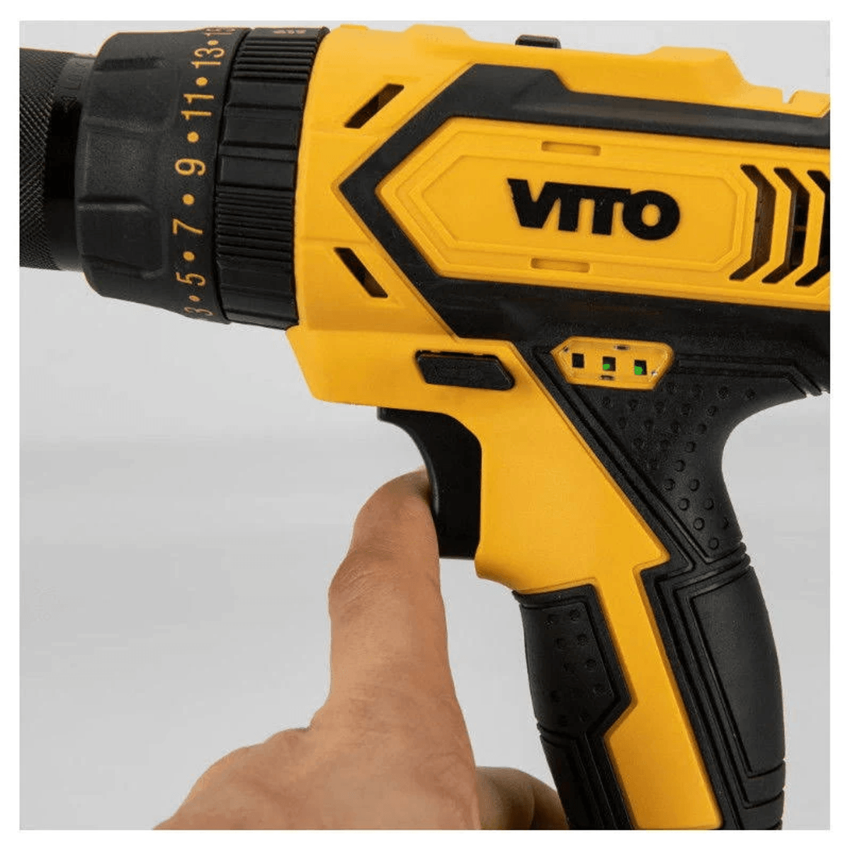 Una mano sostiene un taladro inalámbrico VITO amarillo y negro por el gatillo.
