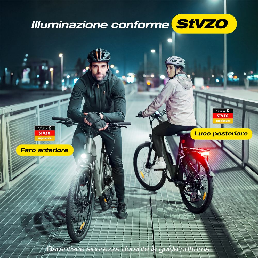Due ciclisti con casco guidano bici elettriche su un ponte di notte con fari e luci.