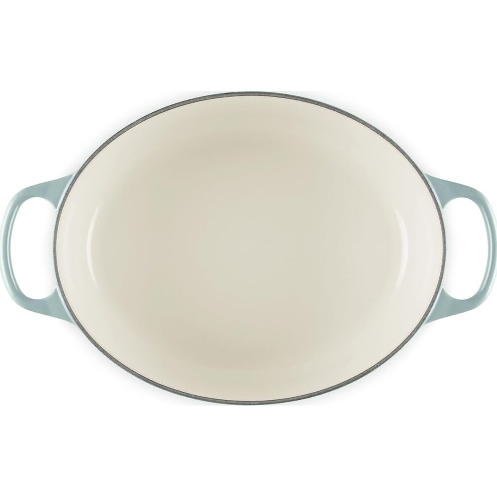 Una pirofila ovale turchese vuota con interno color crema su sfondo bianco.