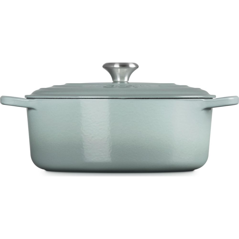 Una casseruola in ghisa azzurra con pomello argentato sul coperchio su sfondo bianco.