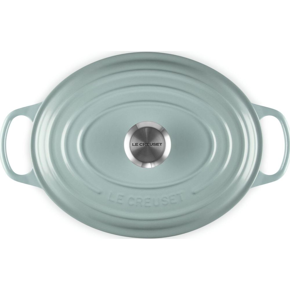 Vista dall'alto di una pentola Le Creuset ovale verde pastello con pomello argentato.