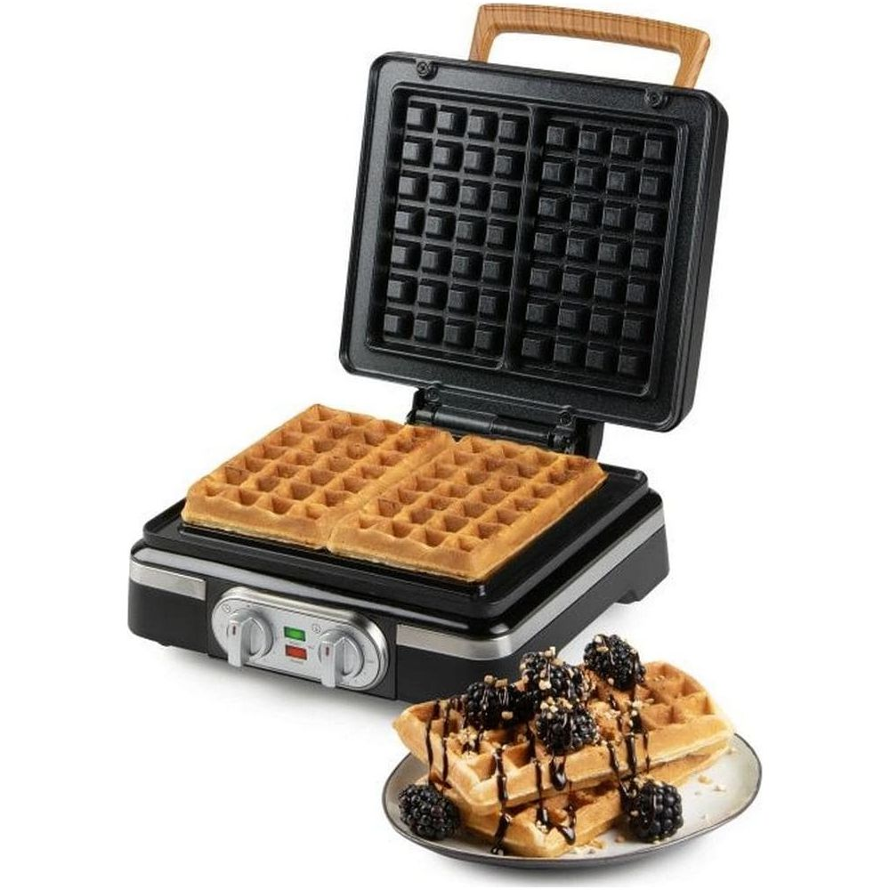 Ein offenes Waffeleisen mit zwei goldenen Waffeln und einem Teller Waffeln mit Brombeeren und Schokolade.