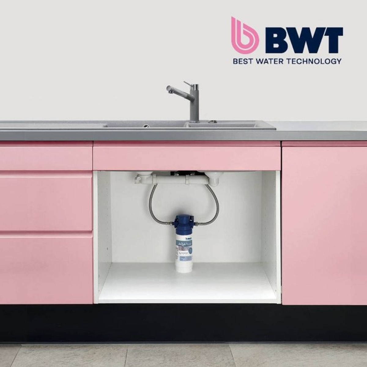 Un filtro dell'acqua BWT blu installato sotto un mobile da cucina rosa con lavello.
