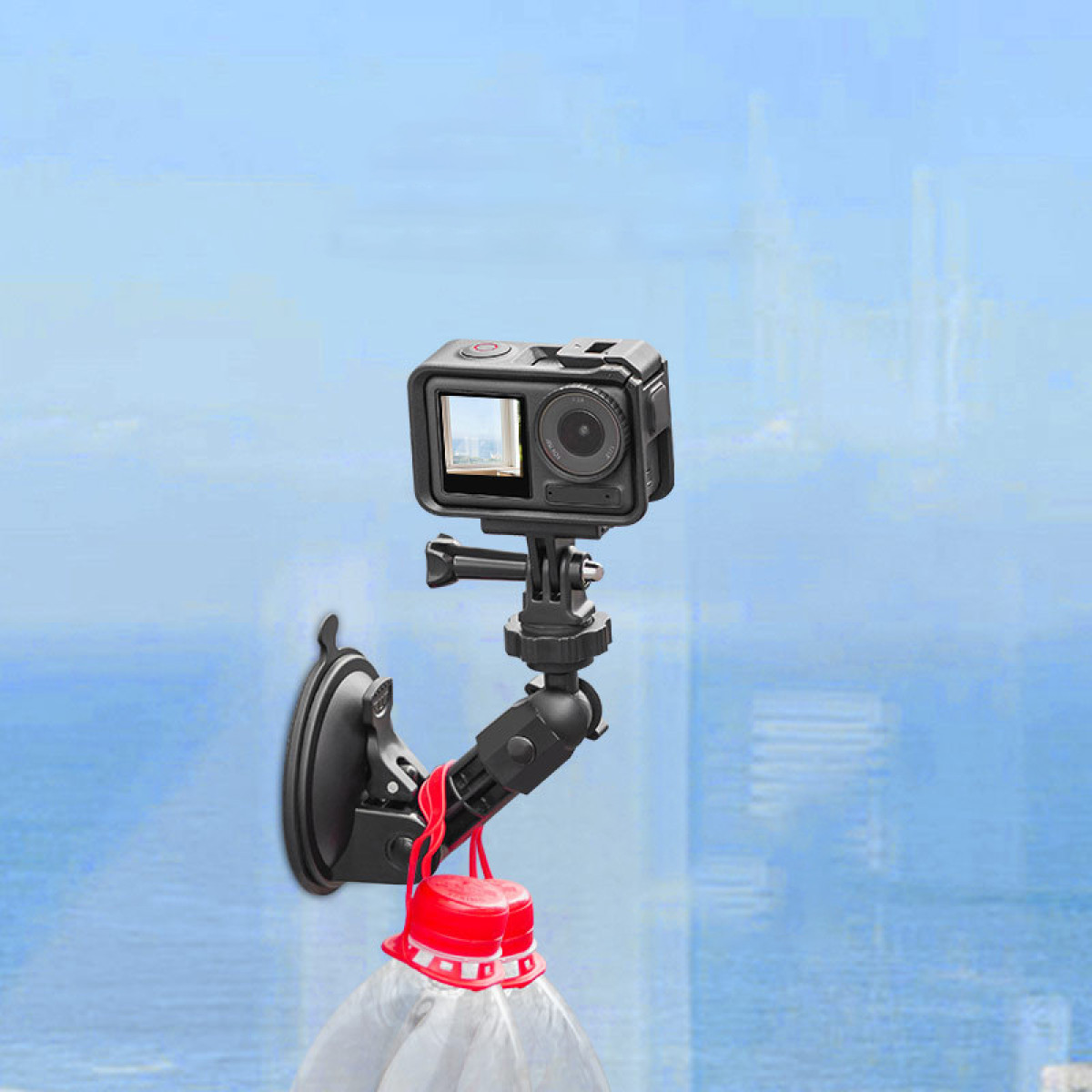 Un'action cam è montata su una superficie di vetro blu con un supporto a ventosa, con due bottiglie appese.