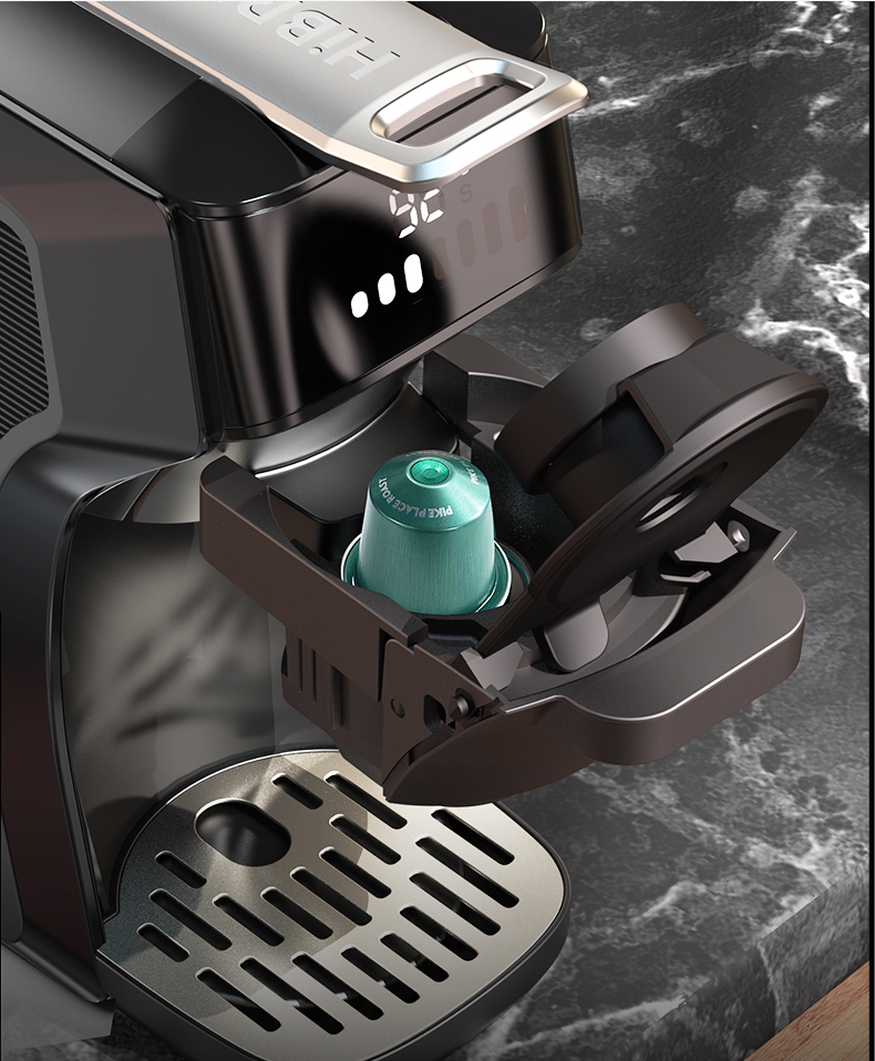 Macchina da caffè nera con portacapsule aperto e capsula verde su ripiano in marmo scuro.