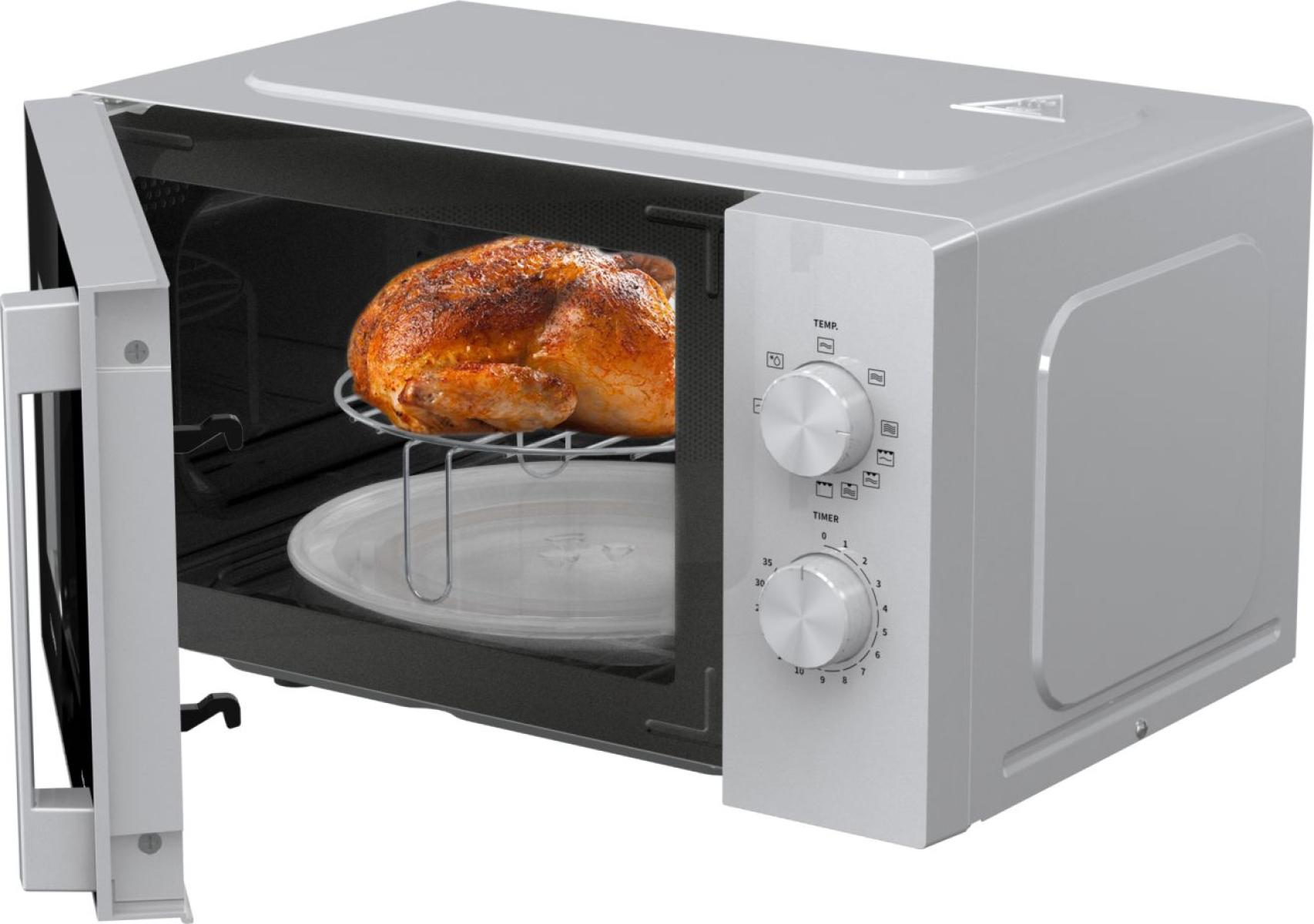 Un microonde argentato con la porta aperta, che mostra un pollo intero arrosto su una griglia.
