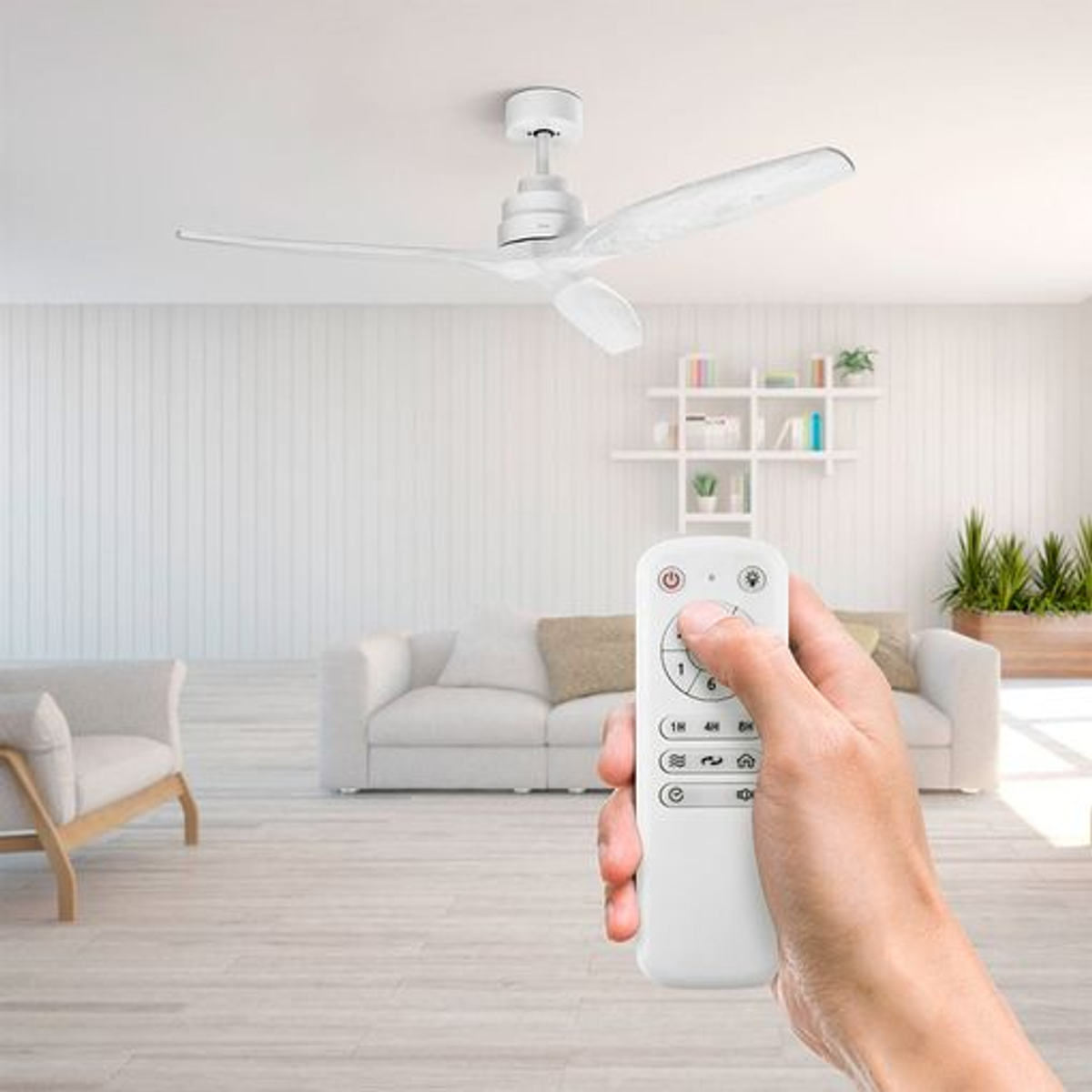 Mano sosteniendo un control remoto que opera un ventilador de techo blanco.