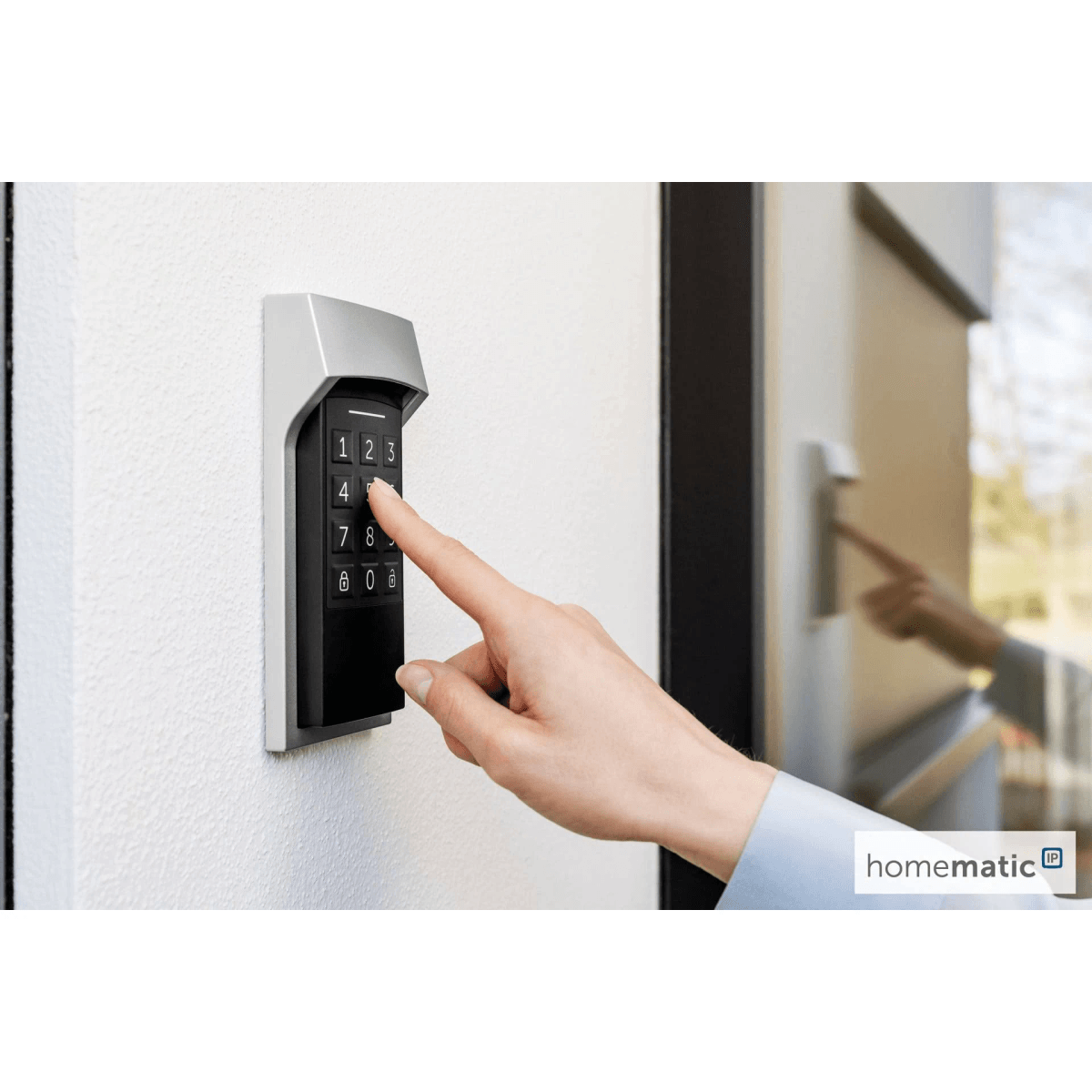 Una mano presiona los botones de un teclado negro montado en una pared blanca junto a una puerta.