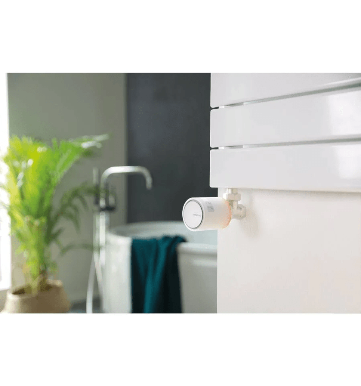 Una válvula de radiador inteligente en un toallero blanco en un baño moderno.