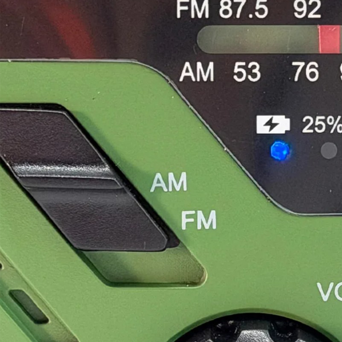 Zbliżenie zielonego radia z przełącznikami AM i FM, wyświetlaczem cyfrowym i baterią 25%.