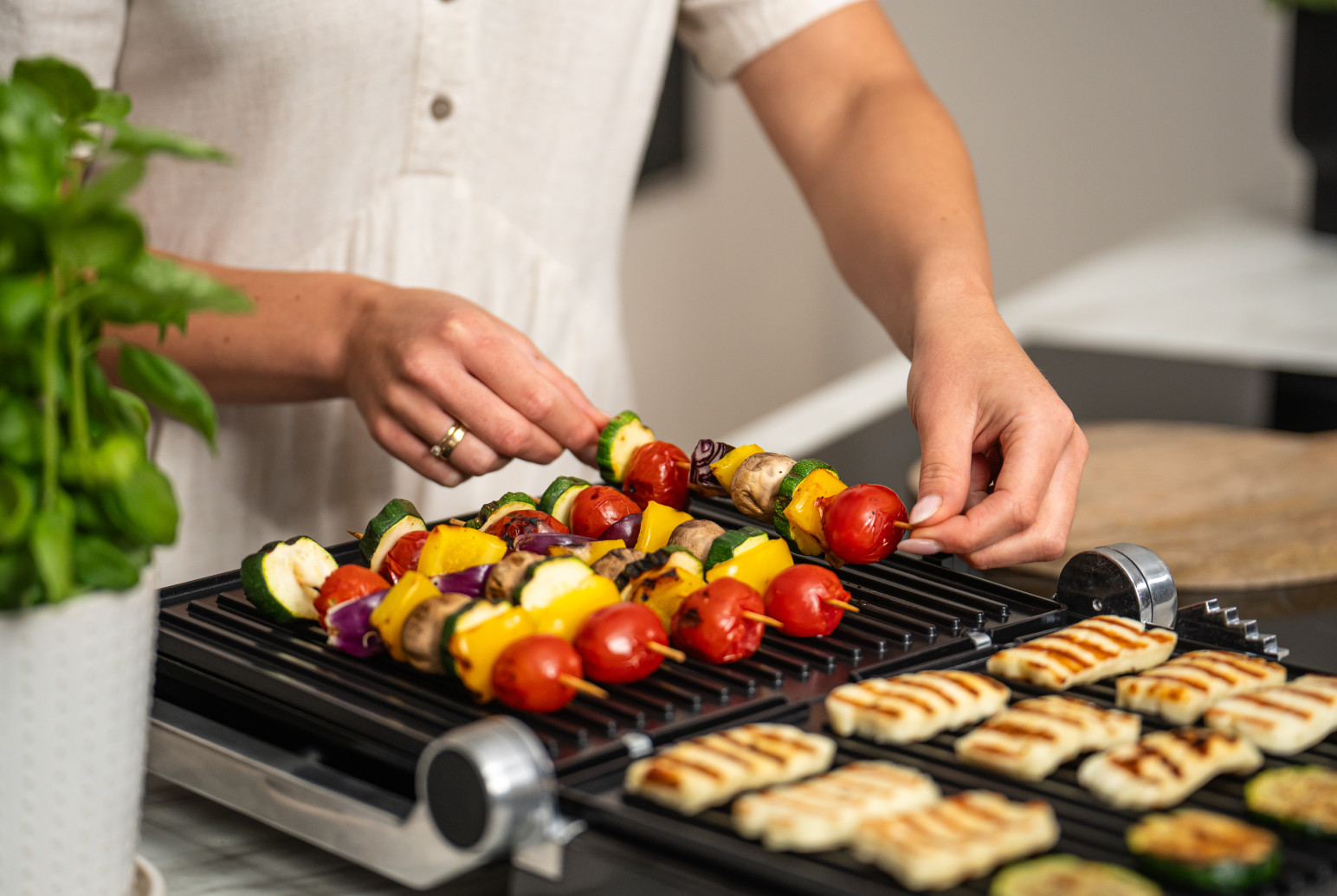 Osoba grillująca szaszłyki warzywne i ser halloumi na grillu.