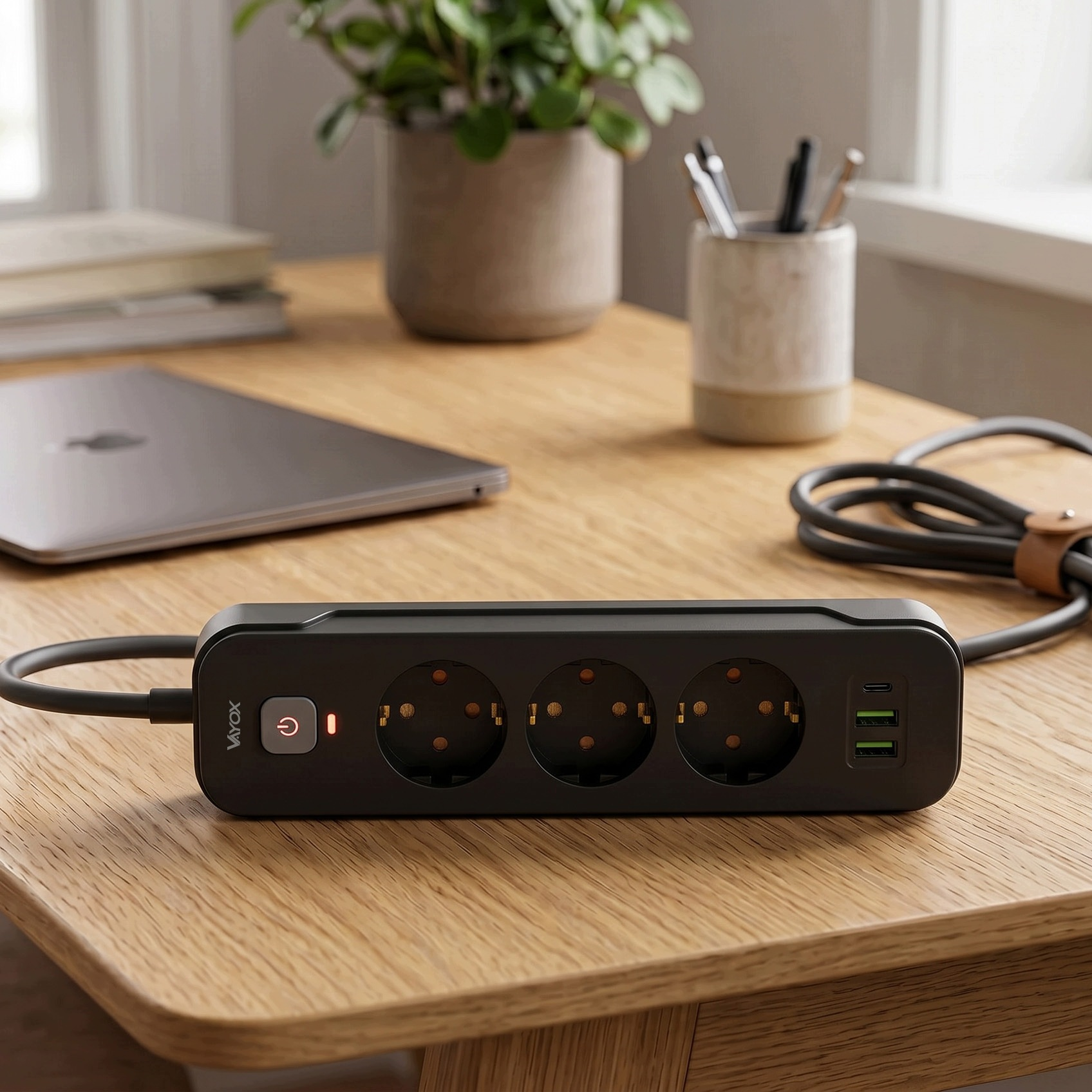 Czarna listwa zasilająca z trzema gniazdami i portami USB na drewnianym biurku.
