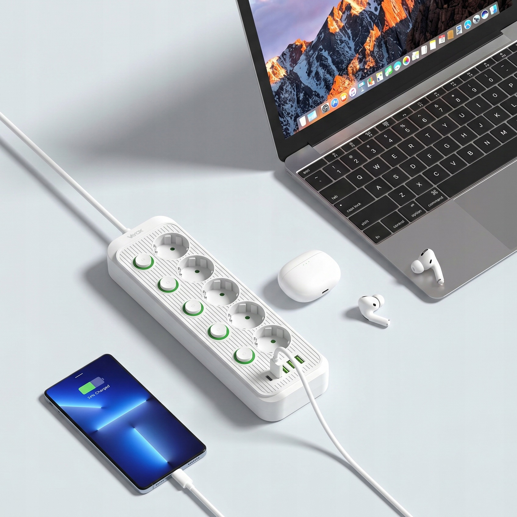 Biała listwa zasilająca z portami USB leży na biurku, podłączona do smartfona, laptopa i słuchawek.