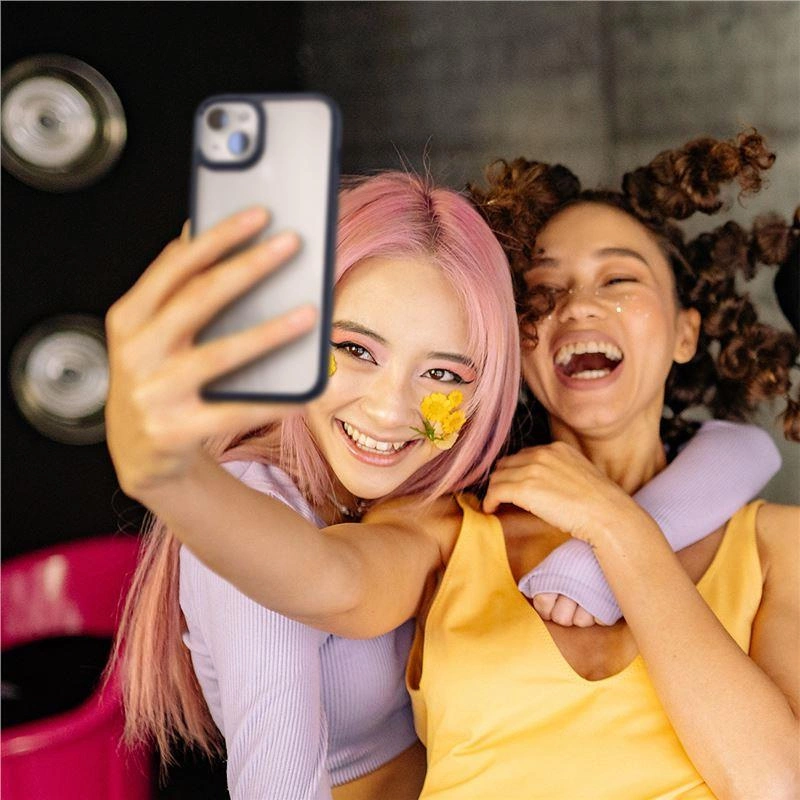 Dwie młode kobiety uśmiechają się i śmieją, robiąc sobie selfie smartfonem, z żółtymi kwiatami na twarzy.