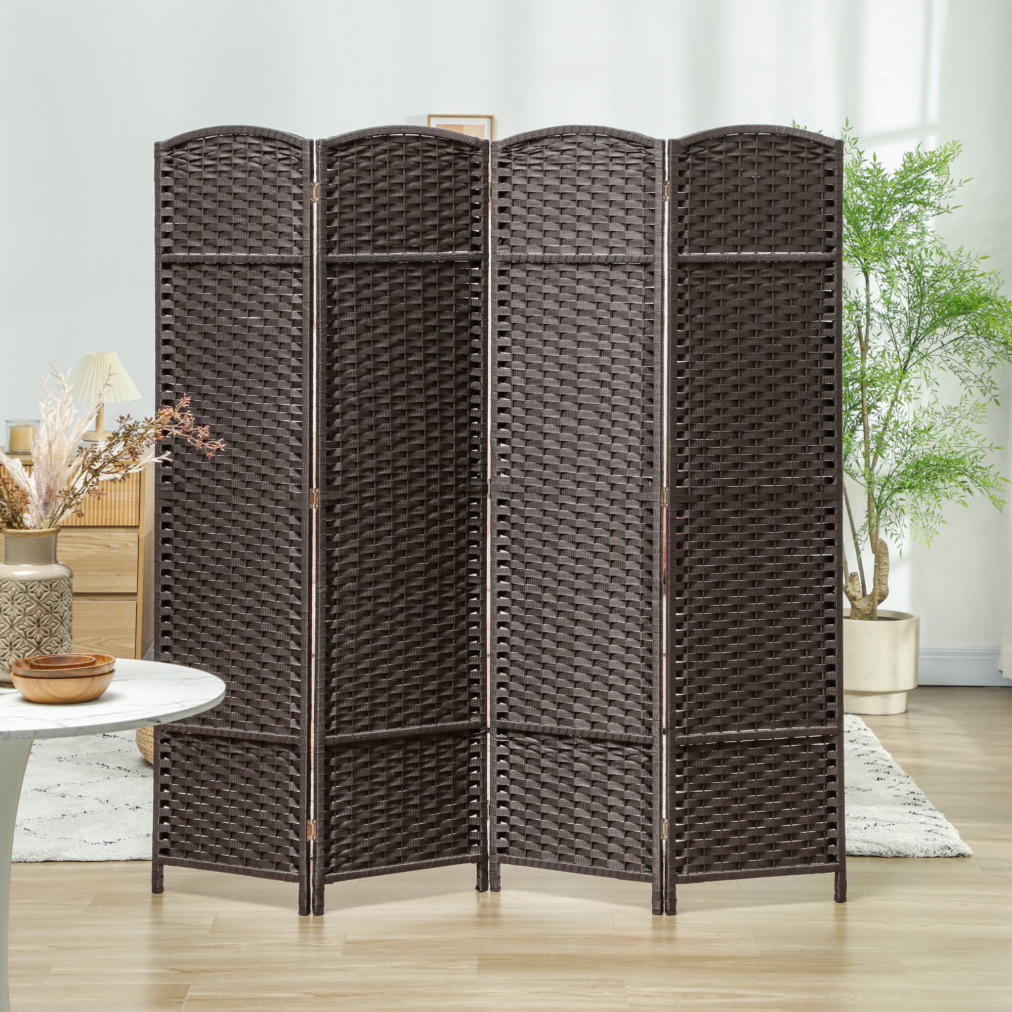 Un biombo marrón de cuatro paneles tejidos se encuentra en una habitación luminosa con planta y muebles.