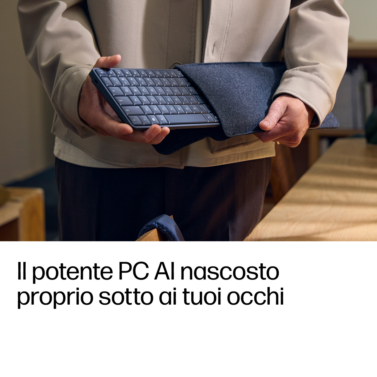 Una persona con giacca chiara estrae una tastiera nera compatta da una custodia in tessuto scuro.