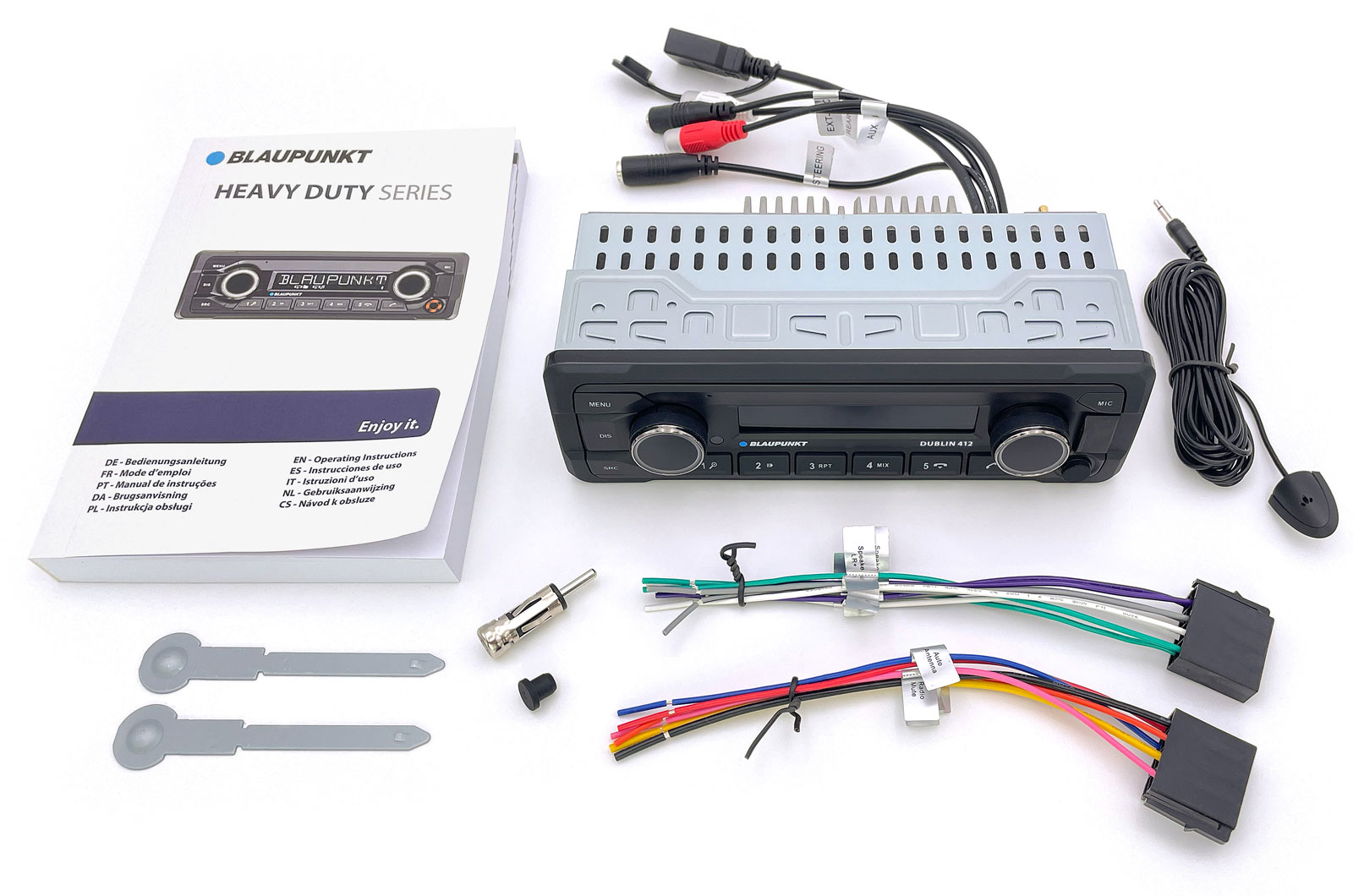 Ein Blaupunkt Heavy Duty Autoradio, das mit Kabeln, Bedienungsanleitung und Einbauzubehör auf weißem Grund liegt.
