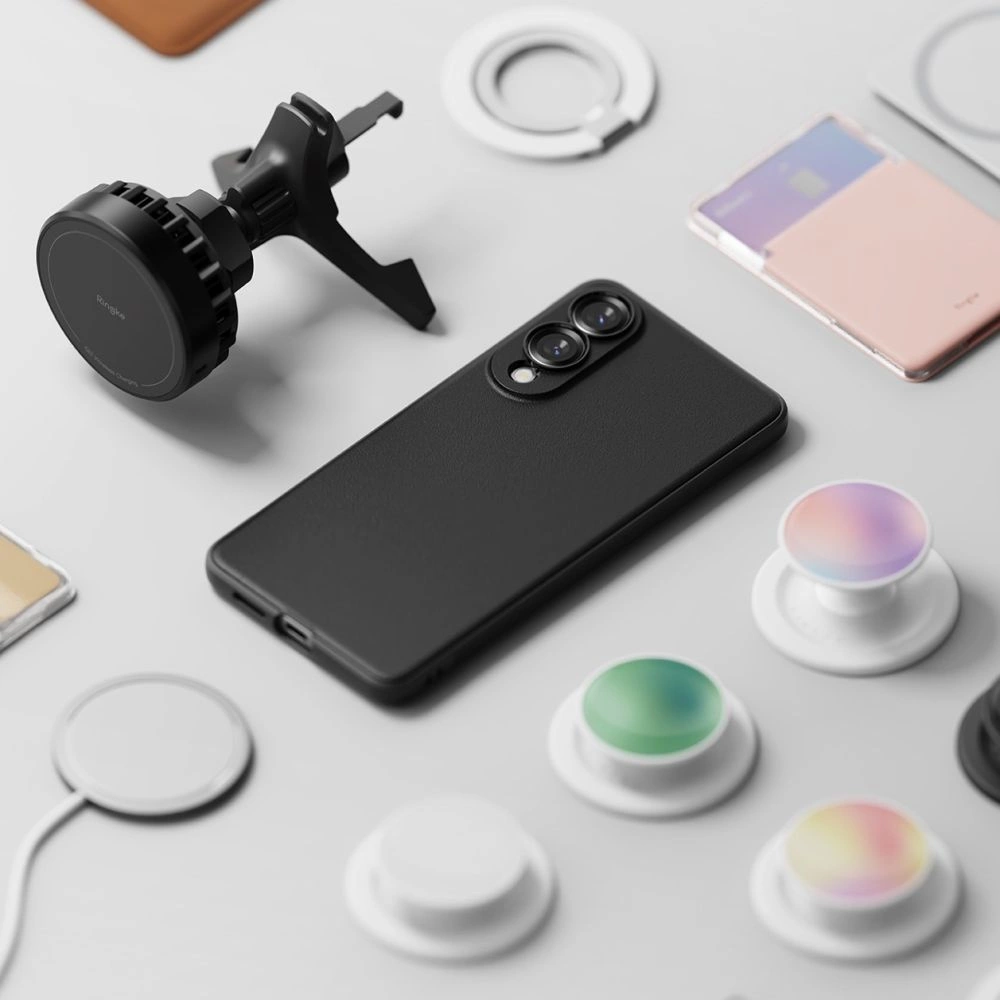 Ein schwarzes Smartphone umgeben von Autohalterung, Pop-Sockets und Ladegeräten auf weißem Untergrund.
