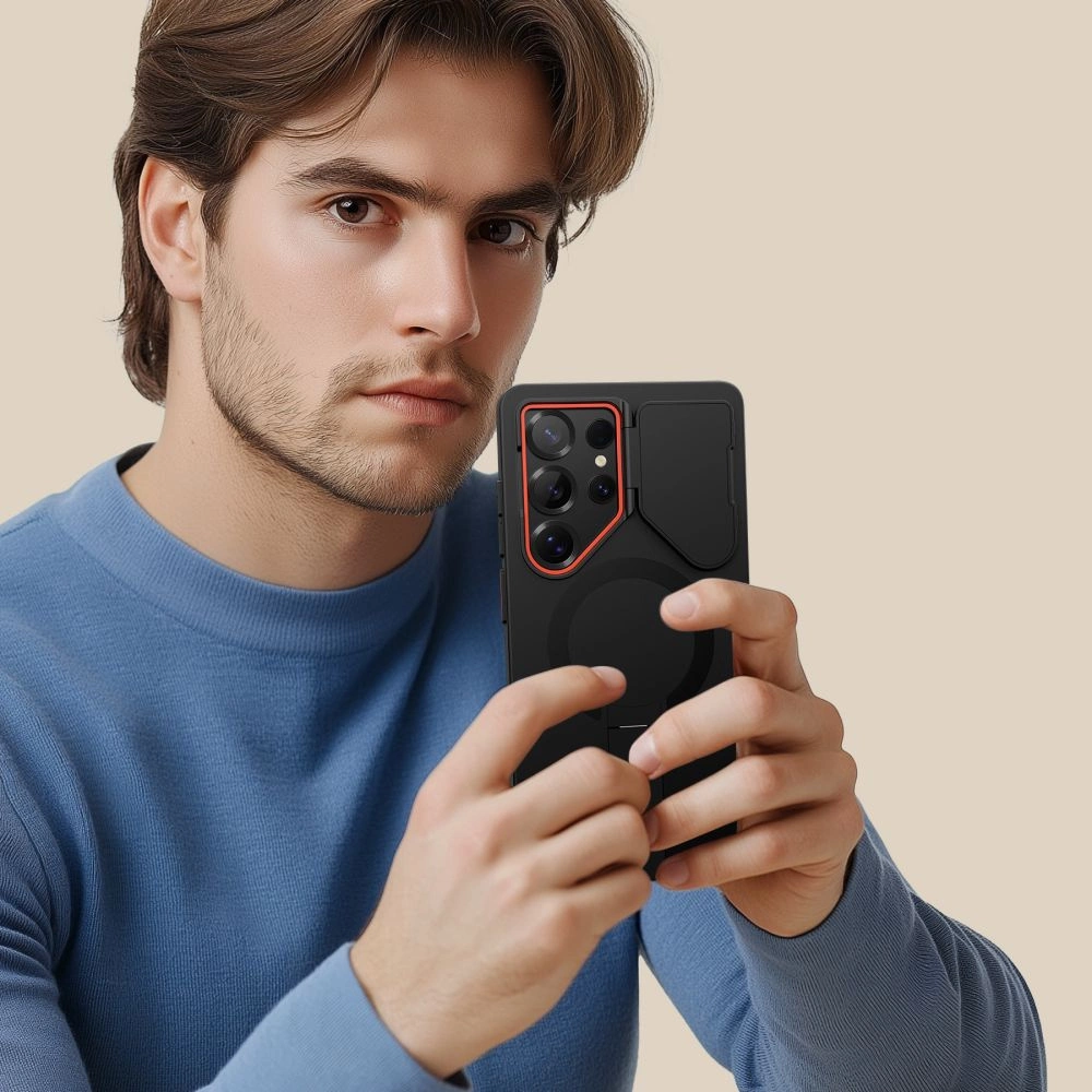 Ein Mann mit blauem Pullover hält ein schwarzes Smartphone mit rotem Kamerarand in den Händen.