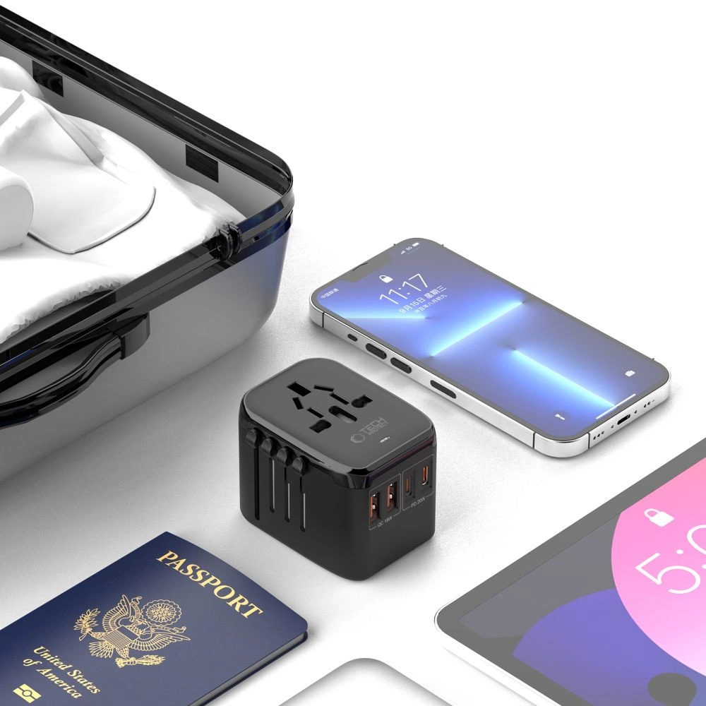 Ein Reiseadapter, ein Smartphone, eine US-Reisepass und Koffer auf weißem Grund.