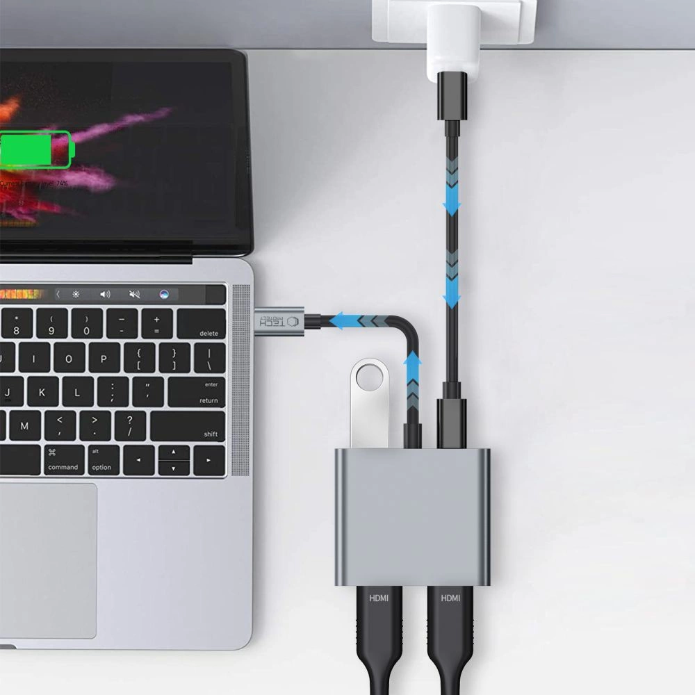 Un computer portatile è collegato a un hub USB-C inserito in un caricatore a muro e a due cavi HDMI.