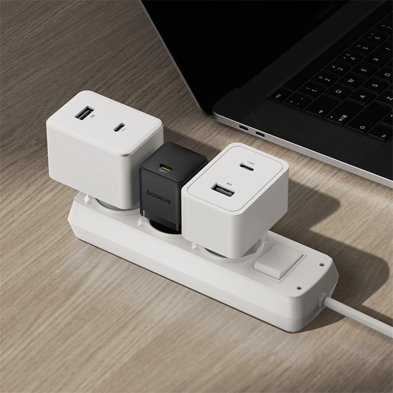 Una ciabatta bianca con caricatori USB collegati si trova su una scrivania in legno.