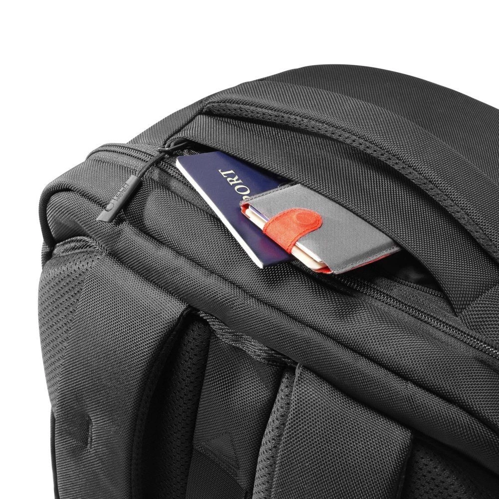 Primo piano di uno zaino nero con un passaporto parzialmente in una tasca con zip.