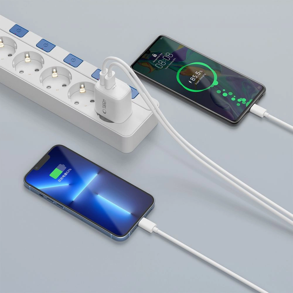 Une multiprise blanche avec deux smartphones connectés en cours de charge.