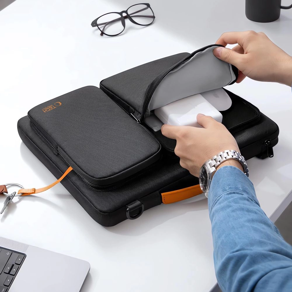 Eine Person öffnet einen schwarzen Tech-Organizer auf einem weißen Schreibtisch.