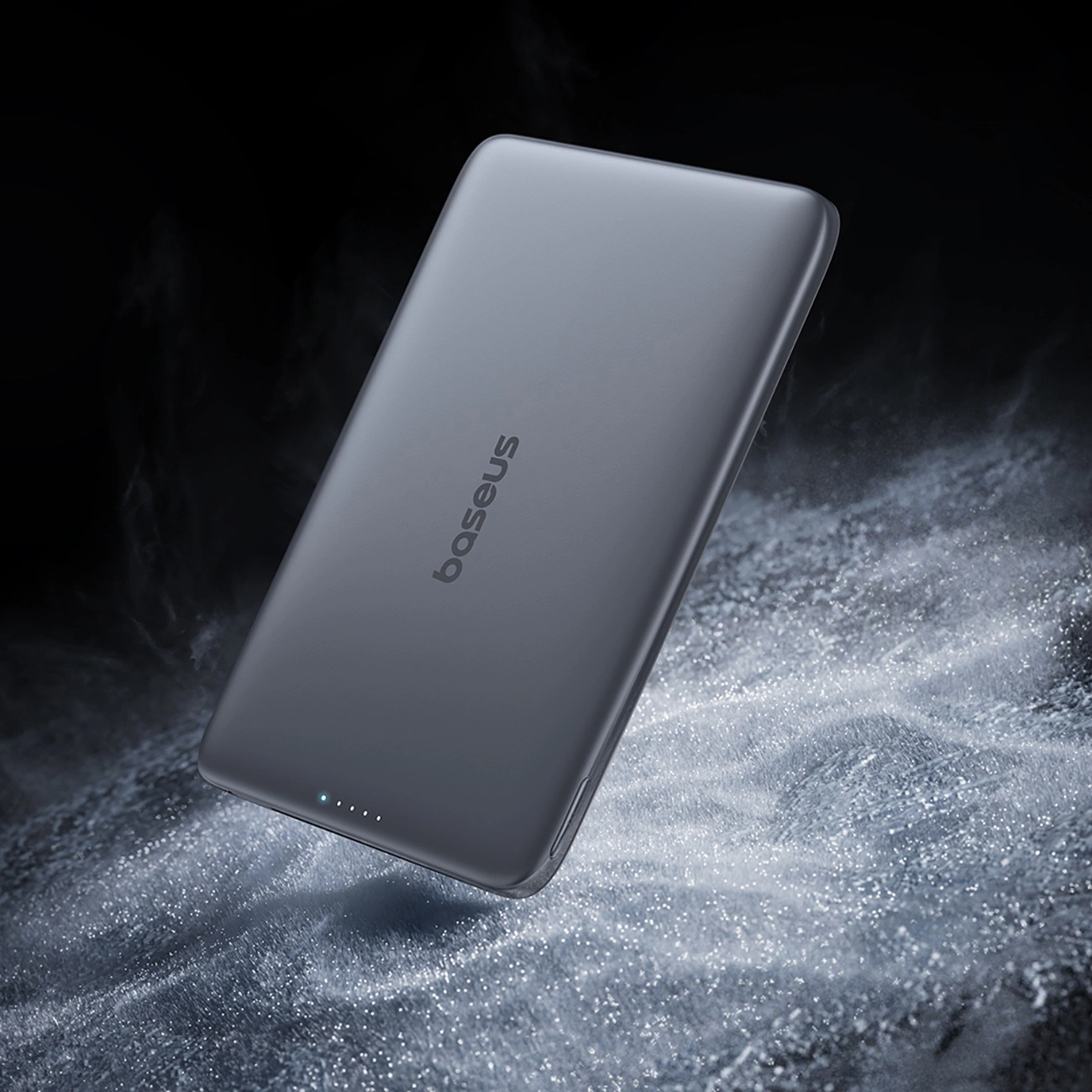 Un power bank Baseus grigio fluttua su una superficie luminosa e testurizzata con effetti di fumo.
