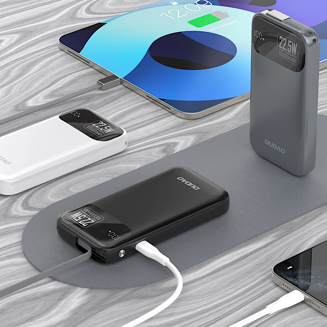 Tre power bank portatili e un tablet in carica su sfondo in legno.