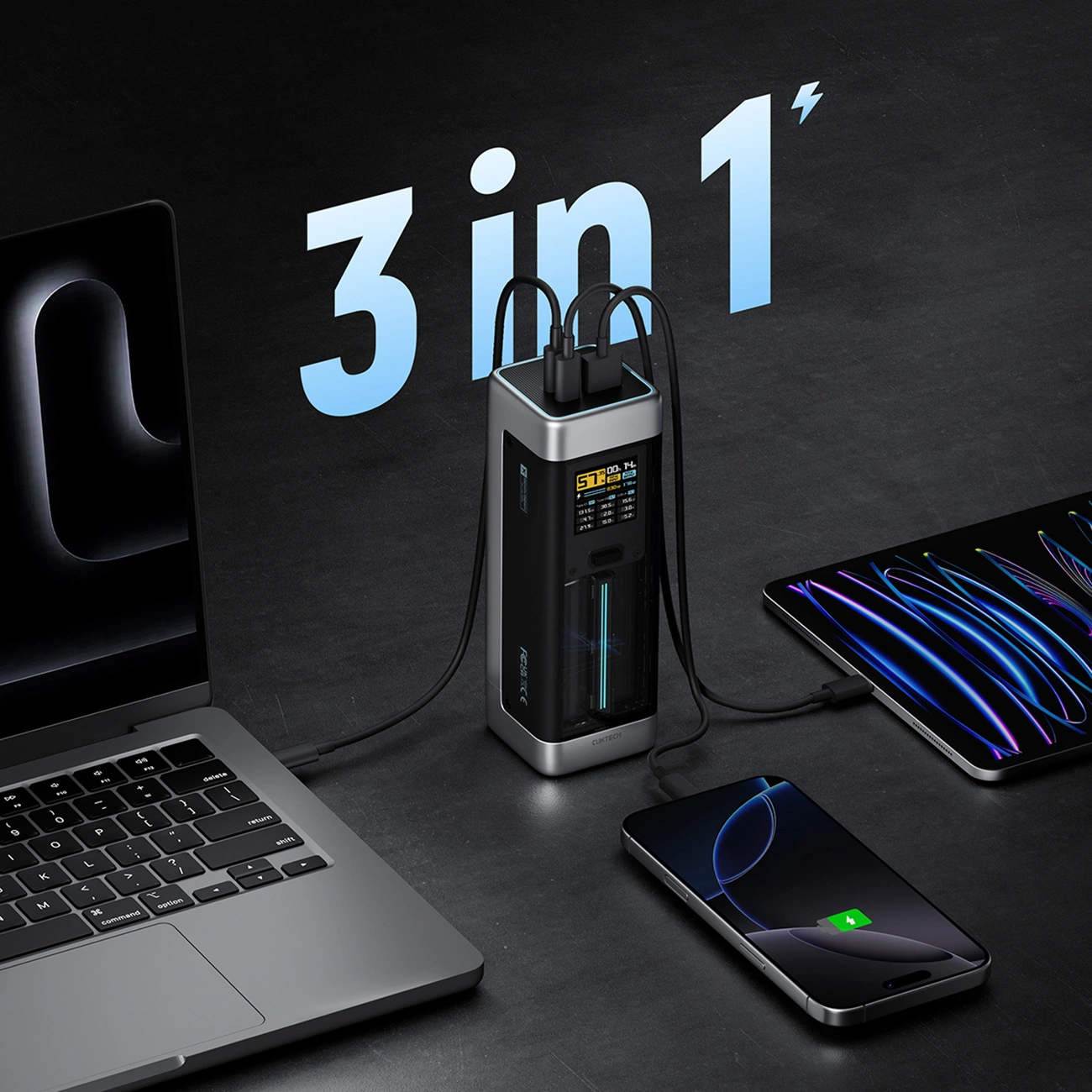 Un caricatore 3 in 1 alimenta contemporaneamente laptop, tablet e smartphone su superficie scura.