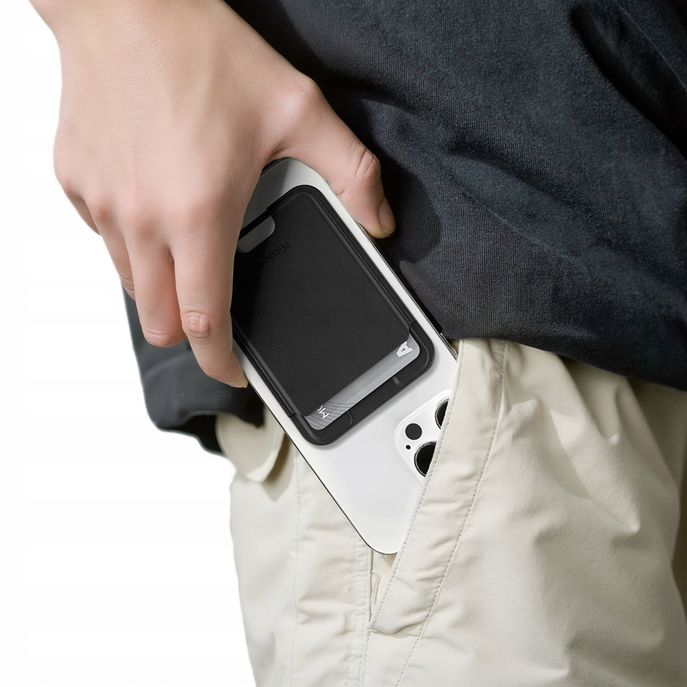 Eine Person steckt ein Smartphone mit schwarzem Kartenhalter in die Tasche einer beigen Hose.