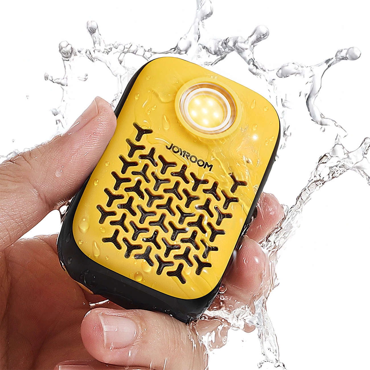 Una mano tiene un altoparlante Joyroom giallo e nero tra schizzi d'acqua su sfondo bianco.