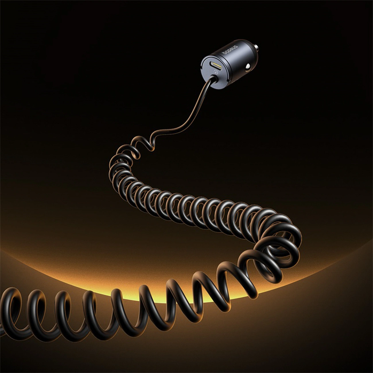 Un cavo per caricabatterie per auto nero a spirale con adattatore su sfondo scuro e luce calda.