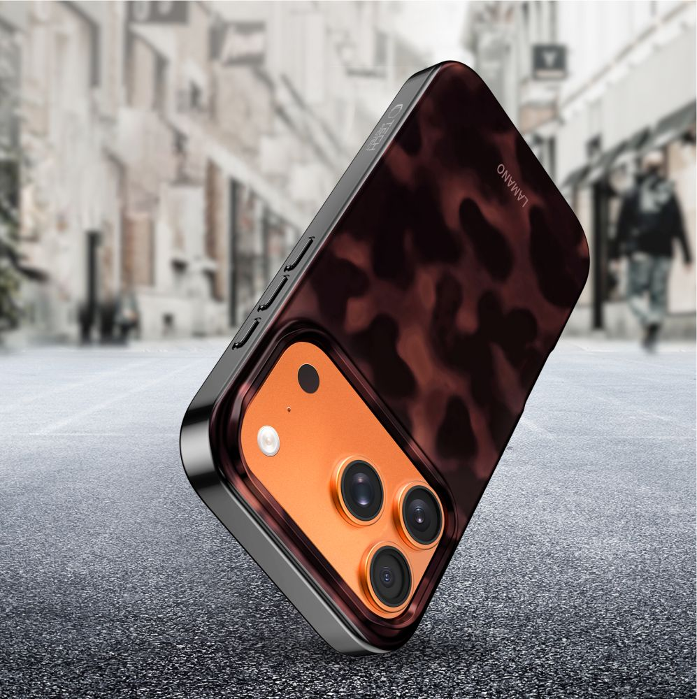 Ein Smartphone in brauner Schildpatt-Hülle steht schräg auf Asphalt vor einer verschwommenen Stadtstraße.