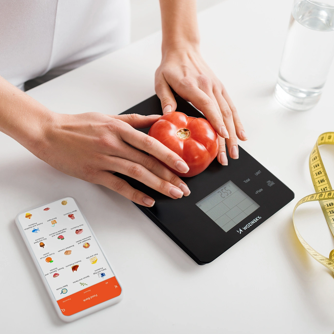 Persona posiziona un pomodoro sulla bilancia, vicino a smartphone con app e metro.