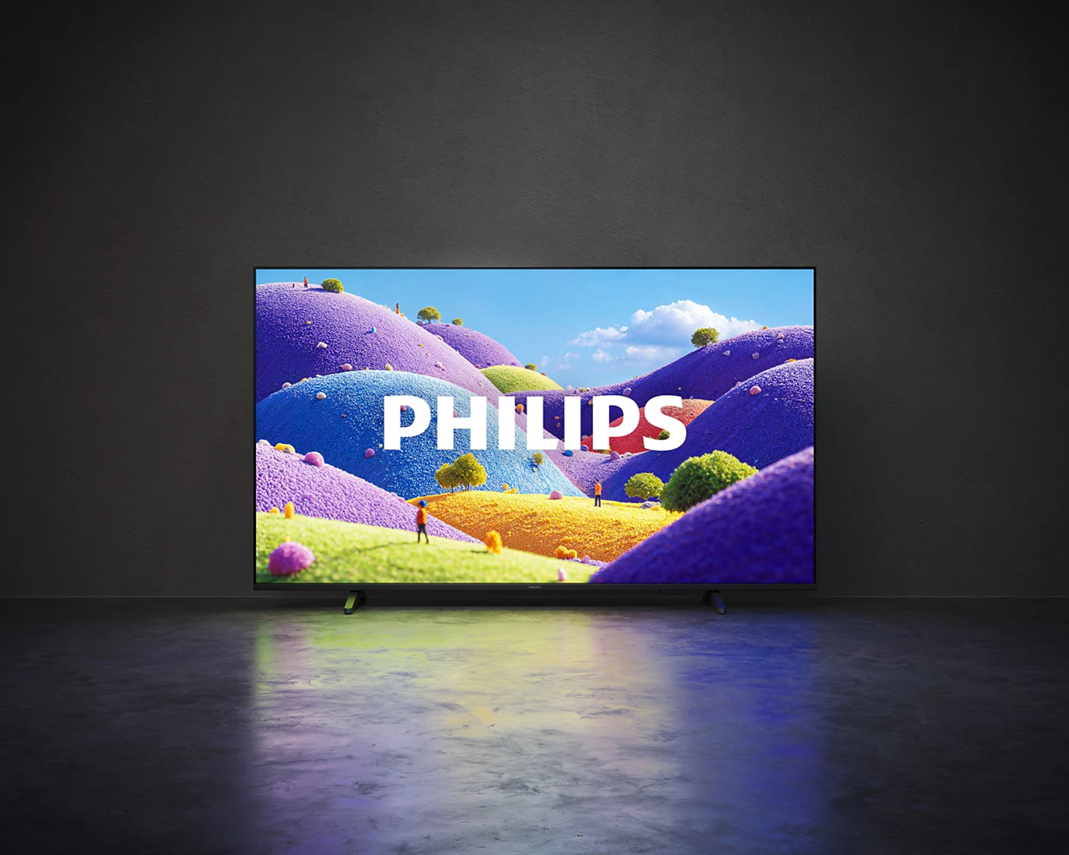 Un televisor Philips muestra un paisaje colorido con colinas moradas, azules y amarillas ante una pared oscura.