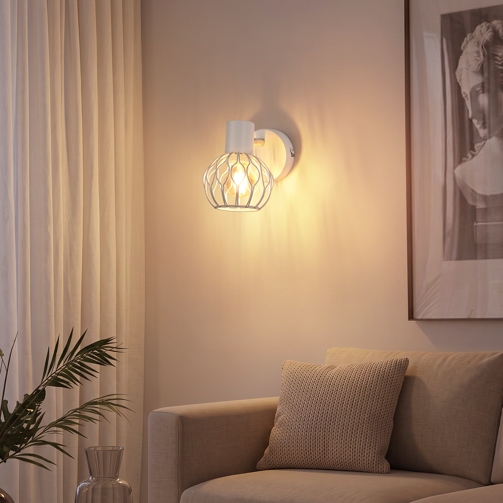Una lámpara de pared blanca con pantalla de alambre ilumina sobre un sofá.