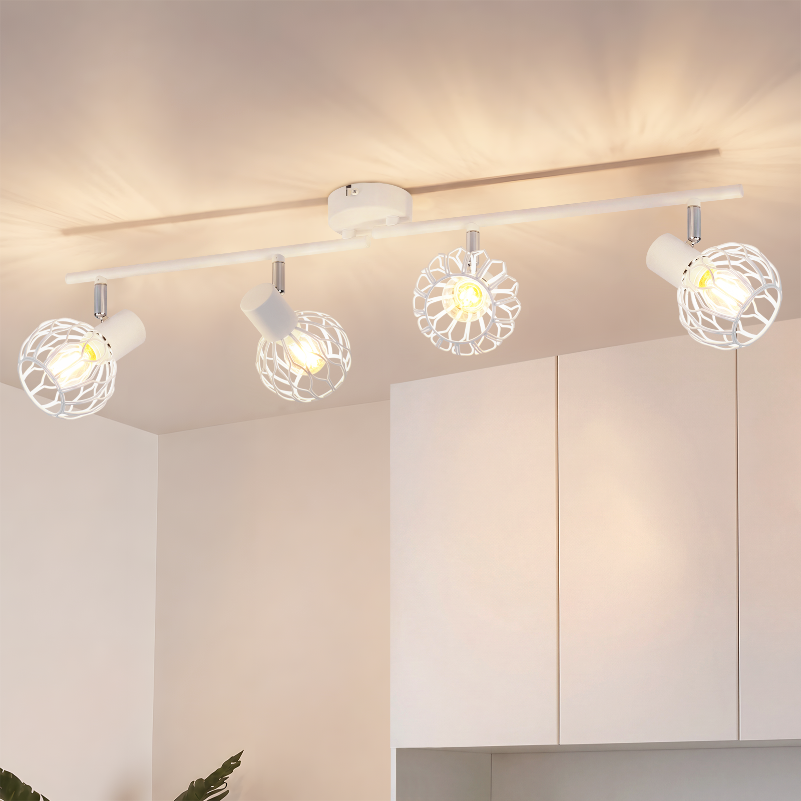 Una lámpara de techo blanca con cuatro focos de malla metálica brillante en una habitación luminosa.