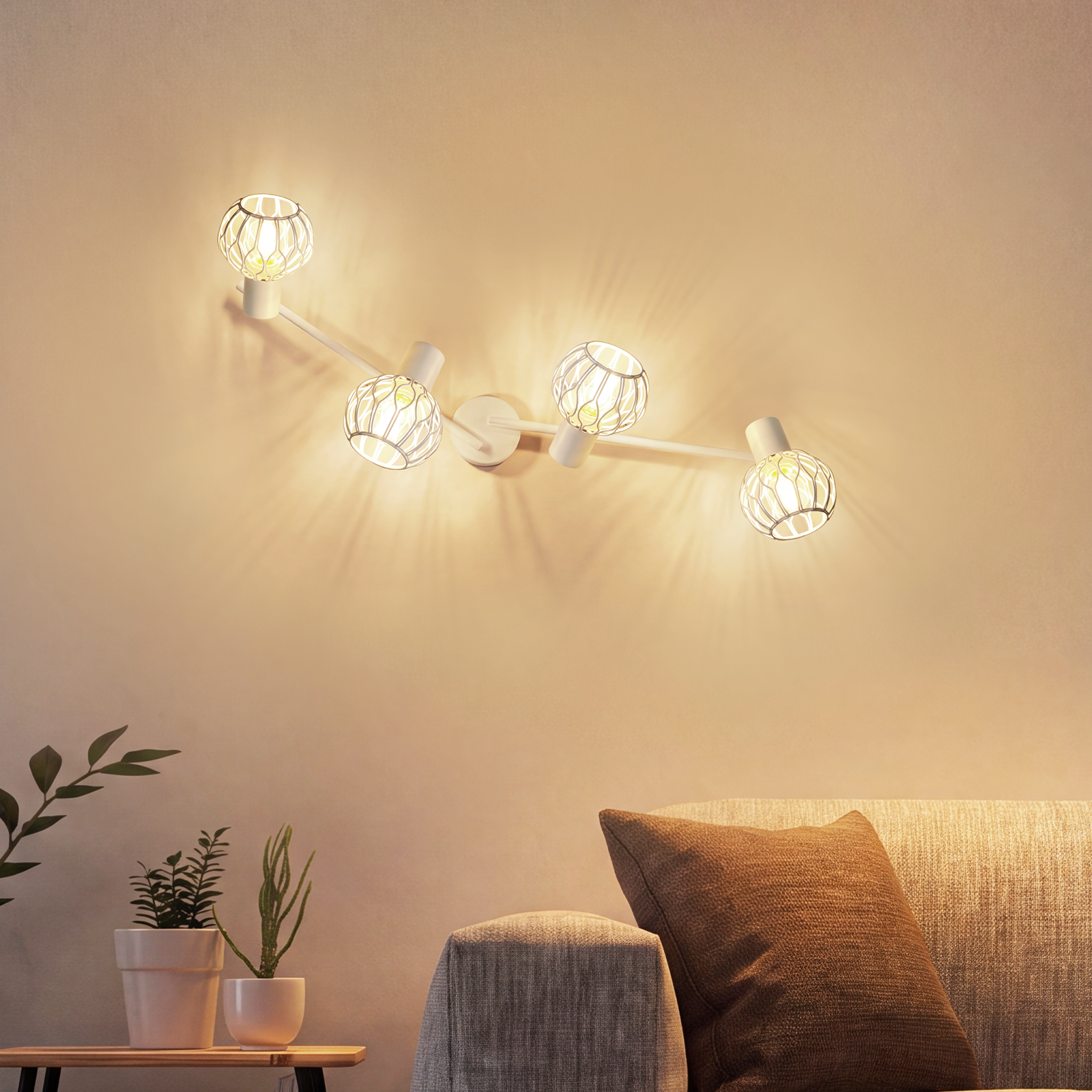 Una lámpara de pared blanca con cuatro pantallas esféricas estampadas ilumina una sala con sofá y plantas.